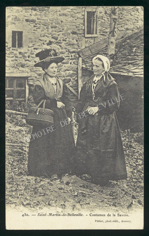 Deux femmes en costumes traditionnels de Savoie à Saint-Martin-de-Belleville vers 1900, photographiées devant une maison de pierre.