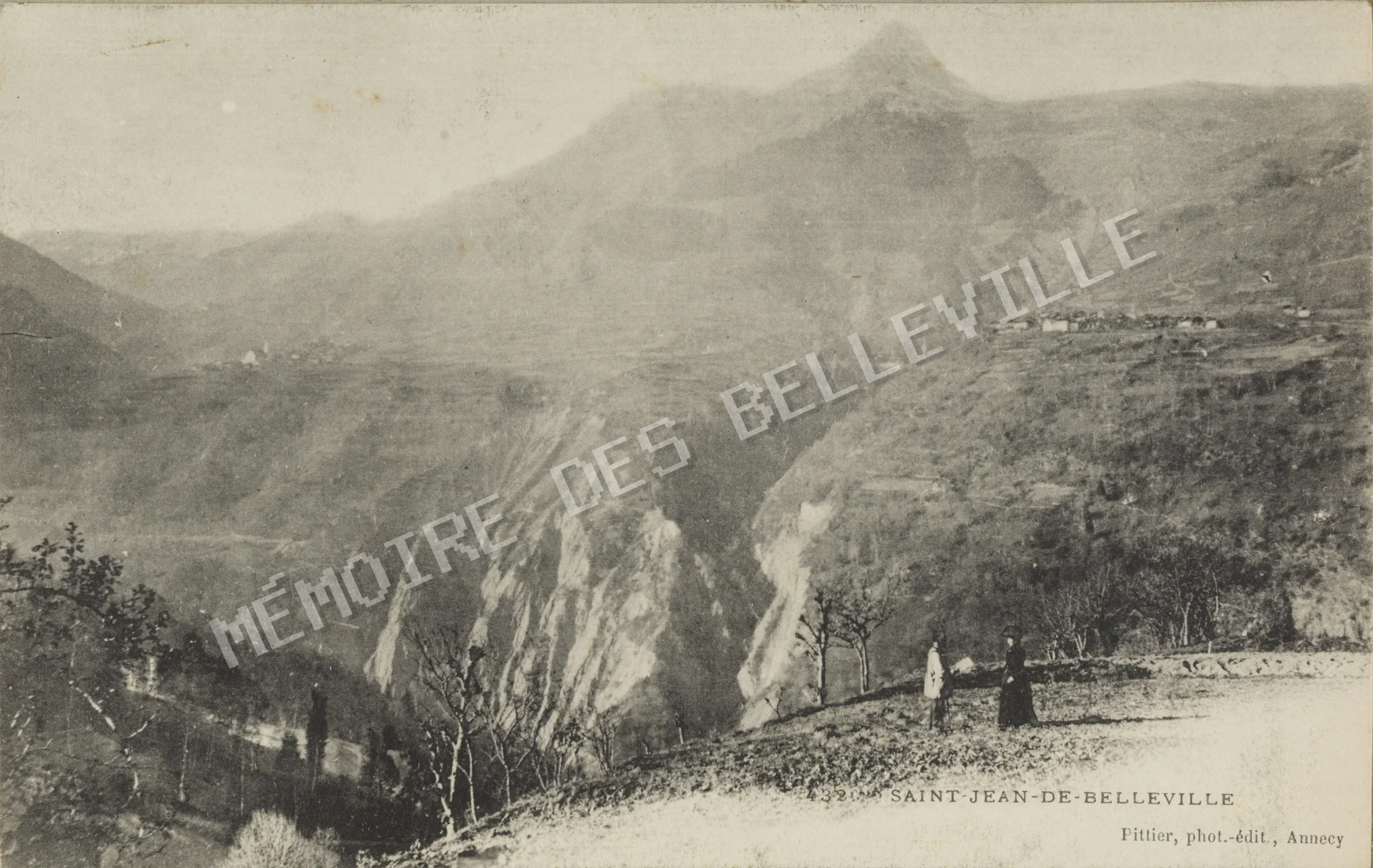 Un couple admire le panorama de Saint-Jean-de-Belleville, dont le village apparaît au loin. Carte postale d’Auguste et Ernest Pittier, 1899-1922. Vue panoramique de Saint-Jean-de-Belleville avec un couple au premier plan et le village visible au loin.