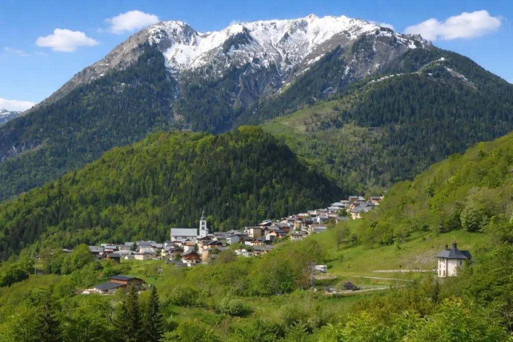 Vue du village de Saint-Jean-de-Belleville en Savoie, entouré de montagnes alpines sous un ciel bleu de fin d'été.